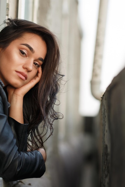 Girl with leather jacket put her her hand to her head and looking from balcony High quality photo