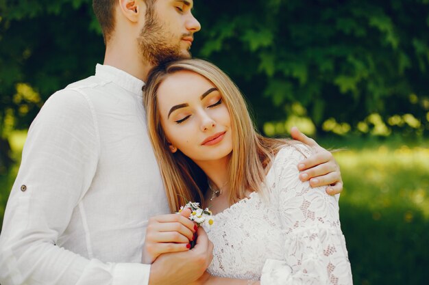 girl with light hair and a white dress in a sunny forest with her boyfriend