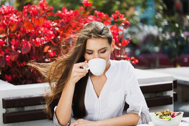 Girl with long hair drinks coffee sitting in the restaurant