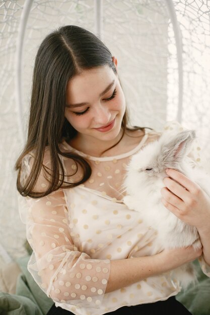 Girl with long hair. White rabbit in girl's arms.