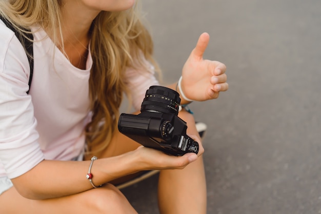 Free photo girl with long hair with skateboard photographing on camera. street, active sports