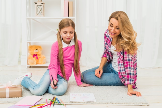 Girl with mother drawing on paper on floor