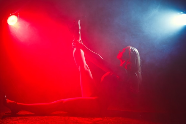 Free Photo girl with perfect slim body. woman posing in bodysuit in red light in the smoke. 