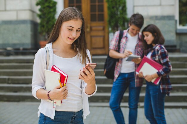 Girl with phone and classmates on street