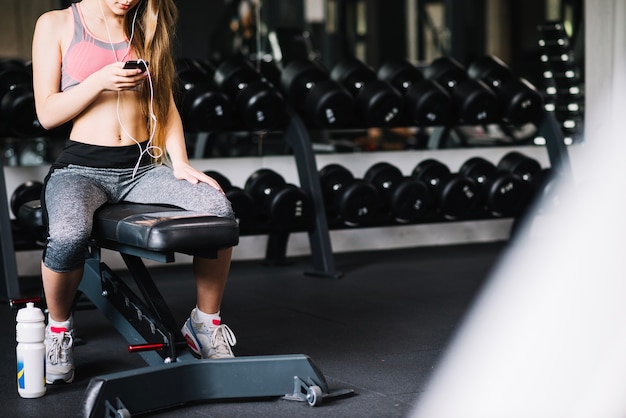 Girl with phone sitting in gym