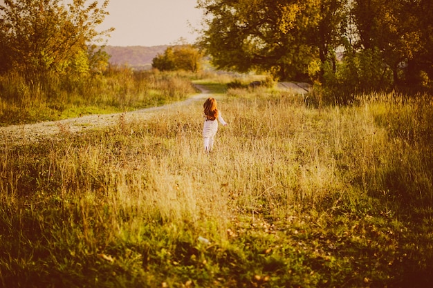 Free photo girl with red hair walks on the green grass