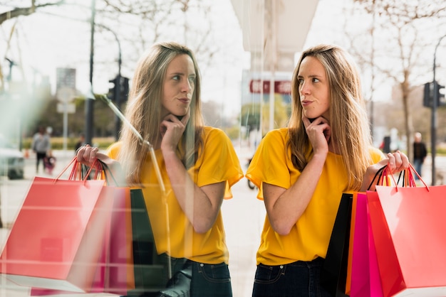 Girl with shopping bags looking at her reflection