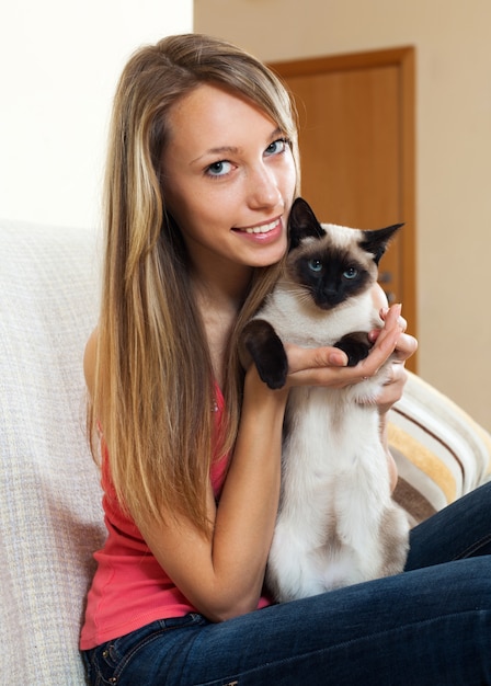 Free Photo girl with a siamese cat  in the room