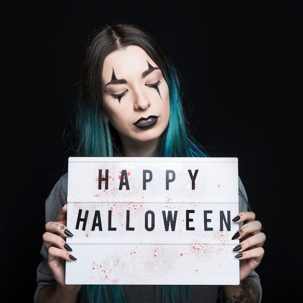 Free photo girl with spooky makeup holding signboard