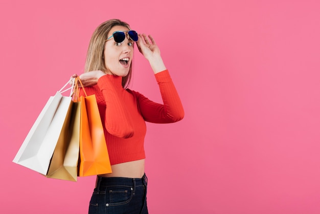 Free photo girl with sunglasses holding shopping bags