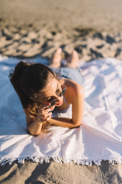 Free photo girl with sunglasses lying on a towel at the beach