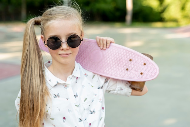 Free Photo girl with sunglasses and pink skateboard