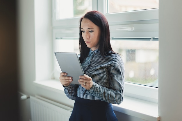 Girl with tablet near window