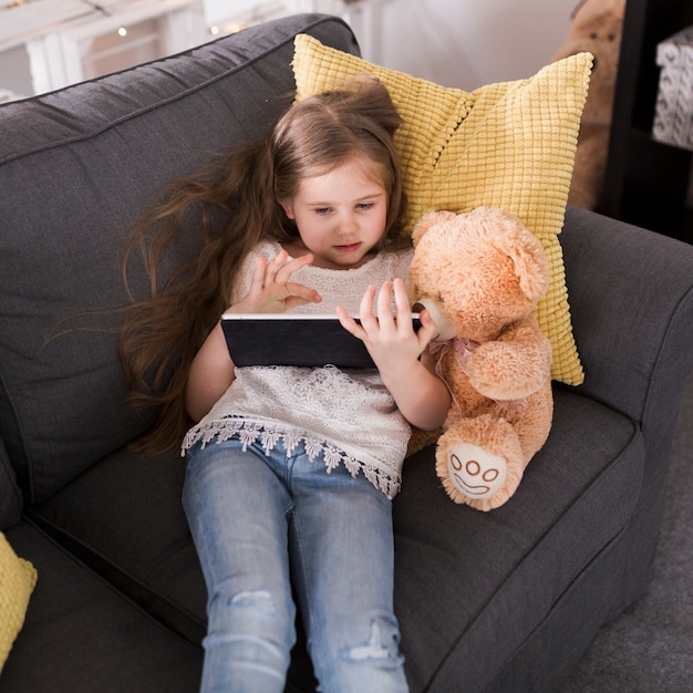 Girl with tablet and teddy