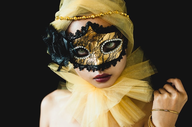 Free photo girl with a yellow ornament on her head and a venetian mask