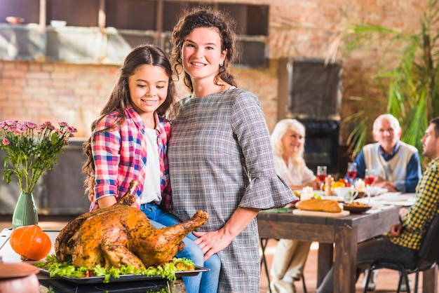 Free photo girl and woman embracing near baked chicken