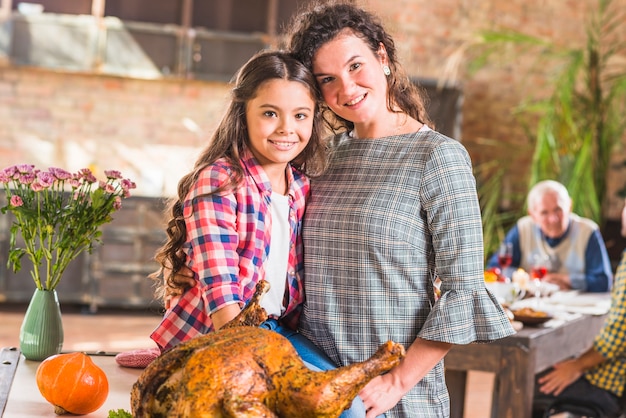 Girl and woman hugging near baked chicken