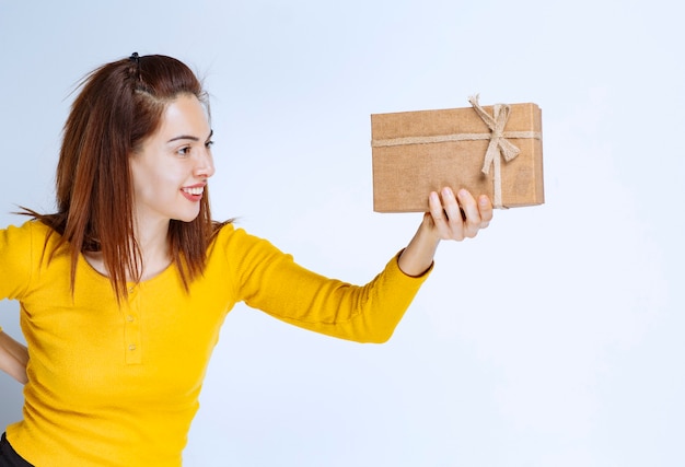 Girl in yellow shirt holding a cardboard gift box.