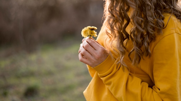 Free photo girl in yellow shirt holding a flower medium view