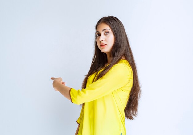 Girl in yellow shirt pointing at somewhere.