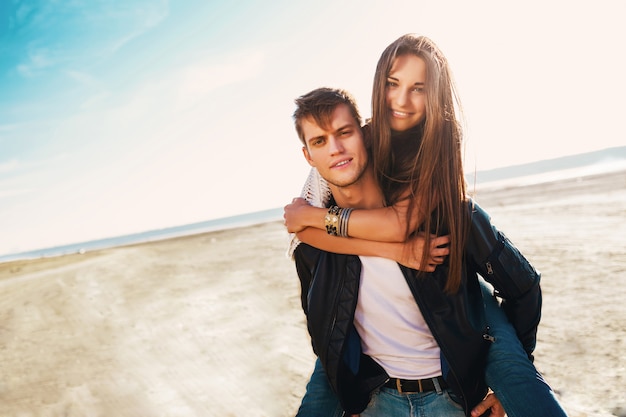 Girlfriend and boyfriend hugging happy. Young pretty couple in love dating on the sunny spring along beach. Warm colors.