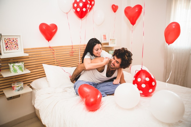 Girlfriend climbing her boyfriend's back on the bed