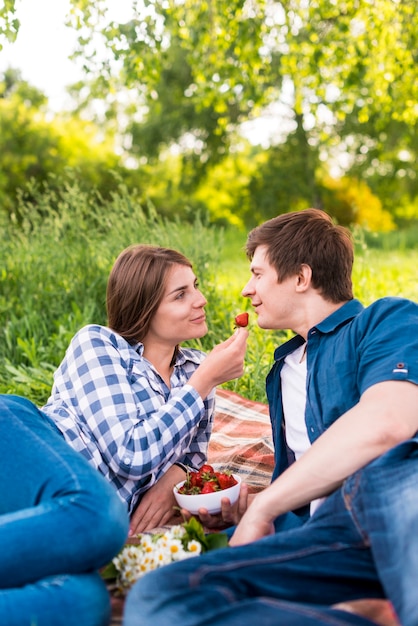 Free photo girlfriend giving strawberry boyfriend during picnic in forest