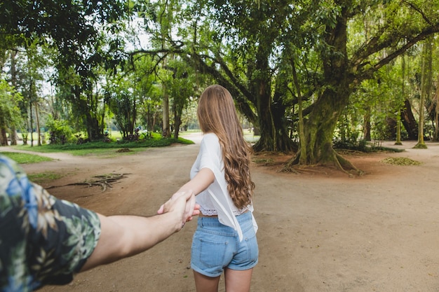 Girlfriend pulling boyfriend towards forest