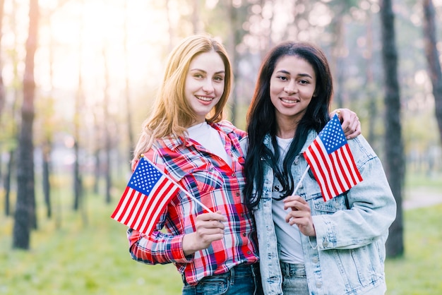 Girlfriends with small American flags standing outdoors