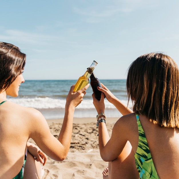 Girls at the beach toasting with beer