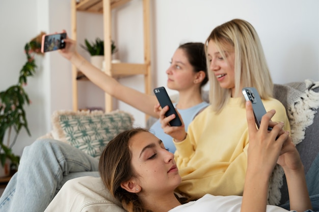 Girls on couch with smartphones side view