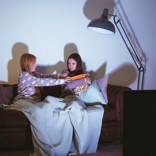 Free photo girls fighting for popcorn watching a movie