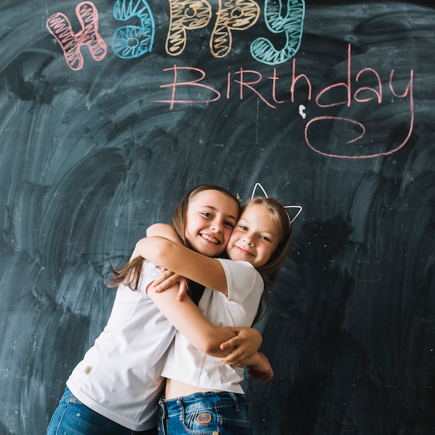 Free photo girls hugging near happy birthday writing