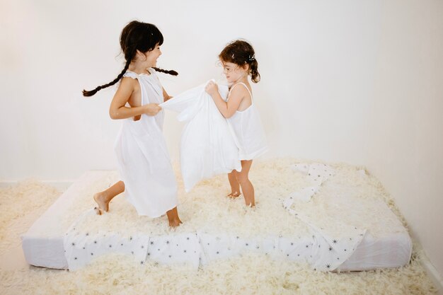 Girls jumping on mattress with pillows