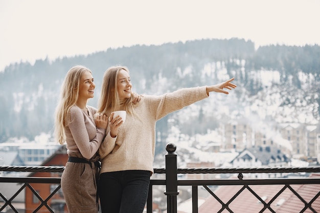 Free photo girls in light clothes. winter coffee on balcony. happy women together.