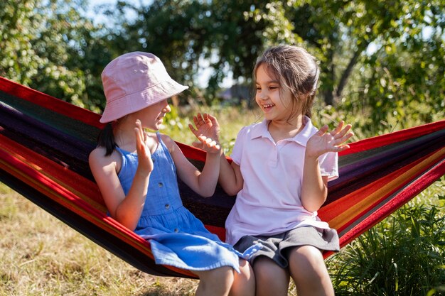 Girls playing outdoors together and sitting in hammock