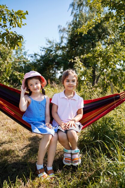 Girls playing outdoors together and sitting in hammock