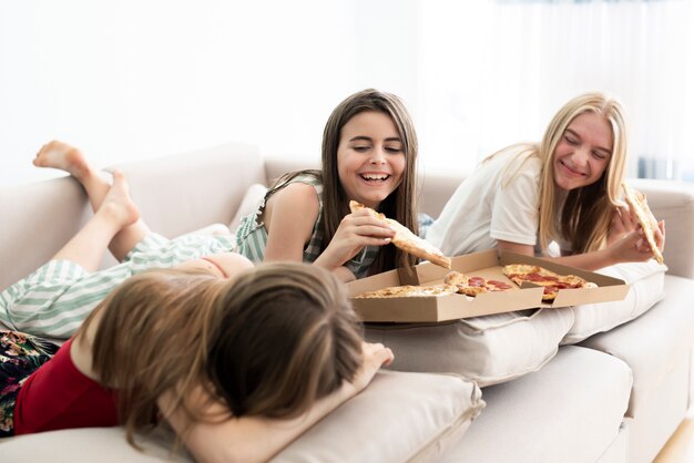 Girls relaxing home and eating pizza