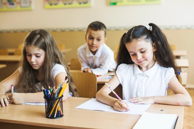 Girls sitting at desk in classroom writing