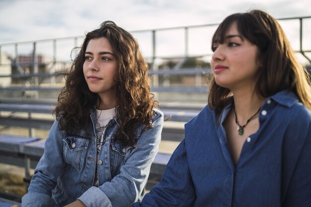 Girls sitting and talking to each other behind a metal fence during daytime