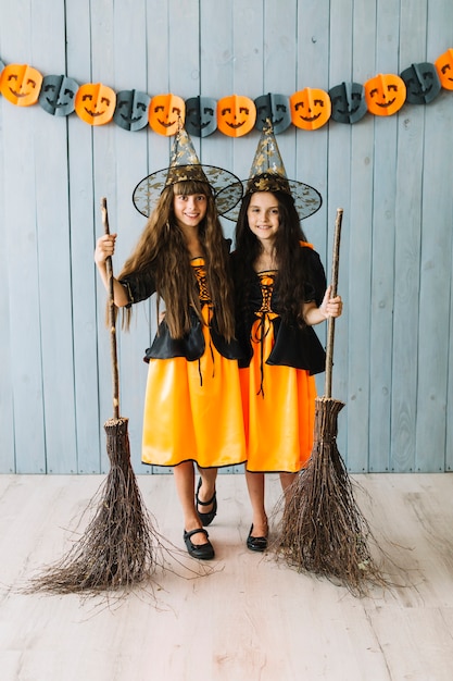 Free photo girls in sorceress clothes hugging and holding broomsticks