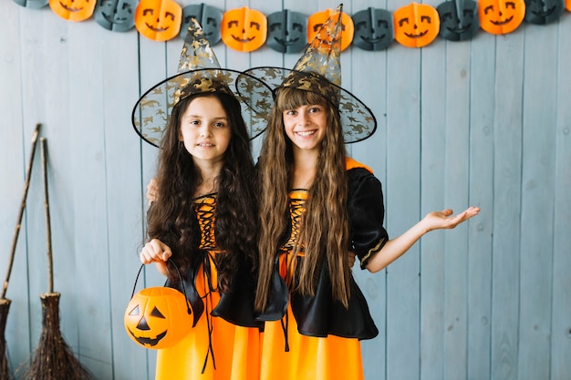 Free photo girls in witch apparel standing in pointy hats and smiling