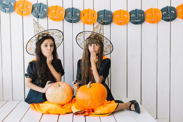 Free Photo girls with halloween pumpkins closing mouth with hand