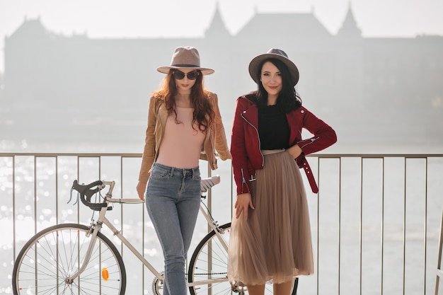 Glad brunette woman in romantic long skirt chilling with best friend on embankment with palace on wall