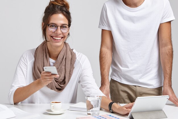 Glad female office worker with smile works with colleague