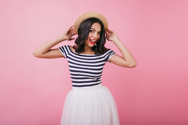 Glad girl in striped t-shirt posing with funny face expression. Indoor portrait of cheerful caucasian woman with brown hair dancing.