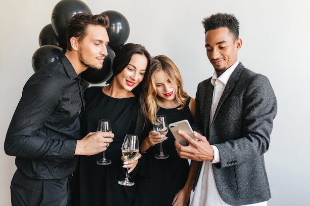 Glad man showing friends last photos on his phone during party