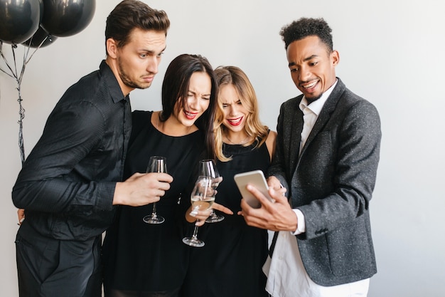 Glad man showing friends last photos on his phone during party