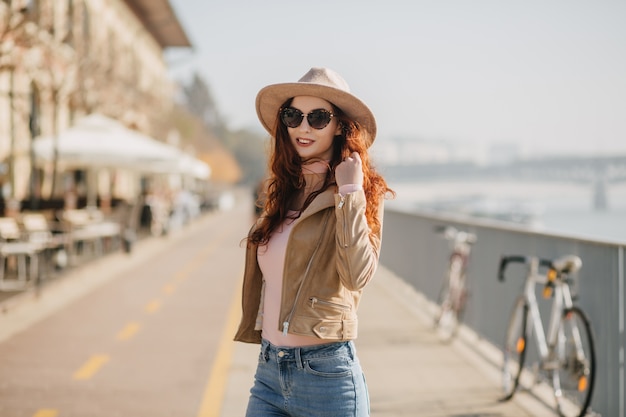 Glad young lady wears beige hat and jacket expressing positive emotions