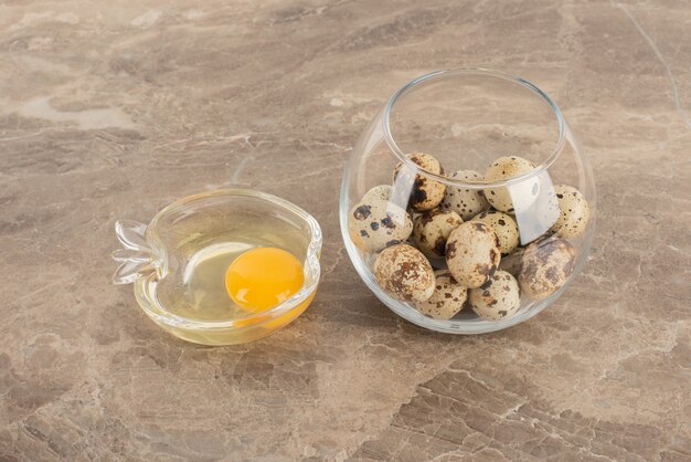 Glass ball of quail eggs and plate of raw egg .